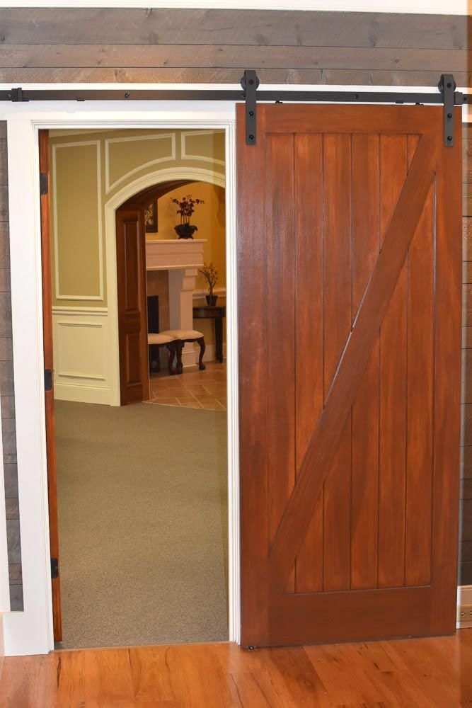Barn door on track, wooden, brown, with diagonal support; doorway to another room.