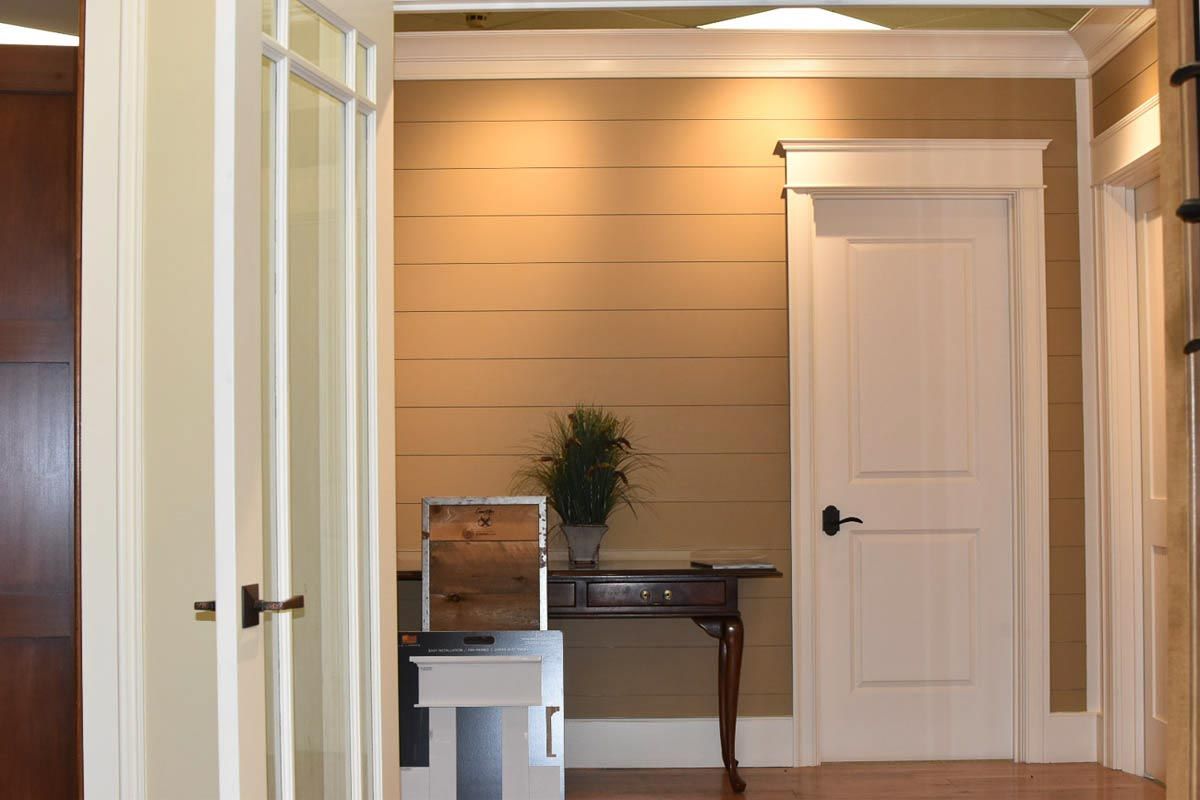 Hallway with tan wall, white door, and small table with plant and mirror.