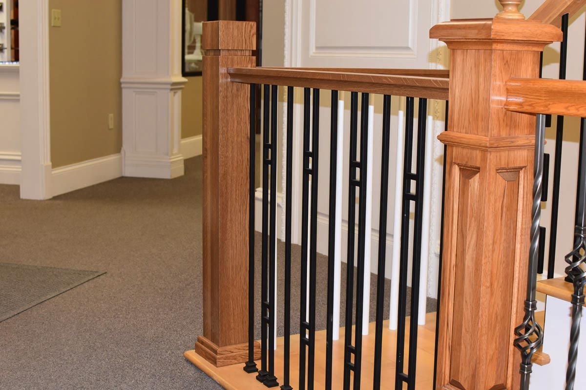 Wooden stair railing with black metal spindles.