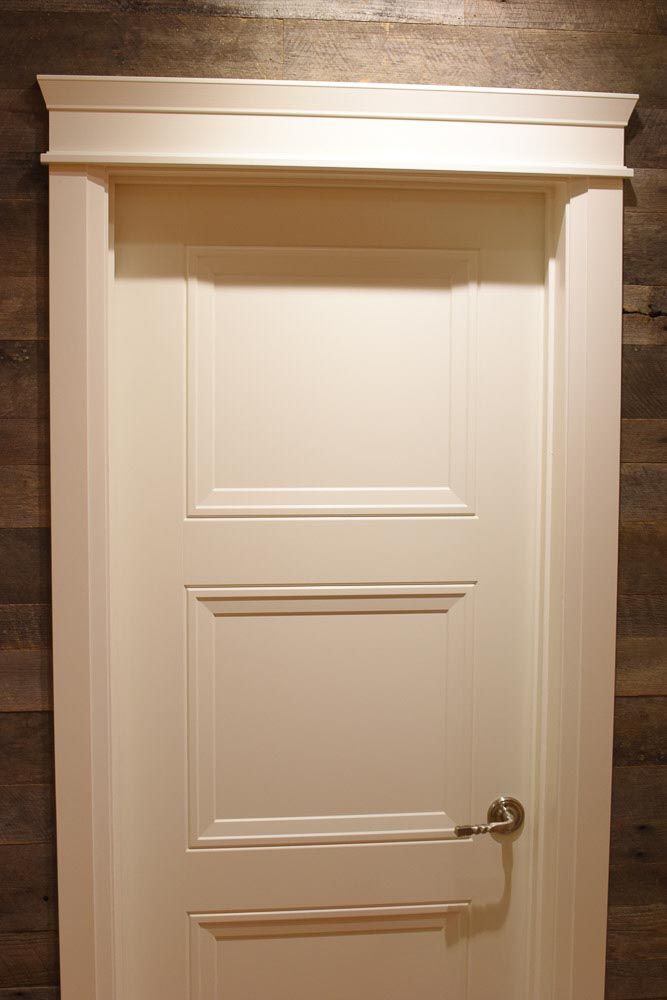 White three-panel door with decorative trim against a wood-paneled wall.