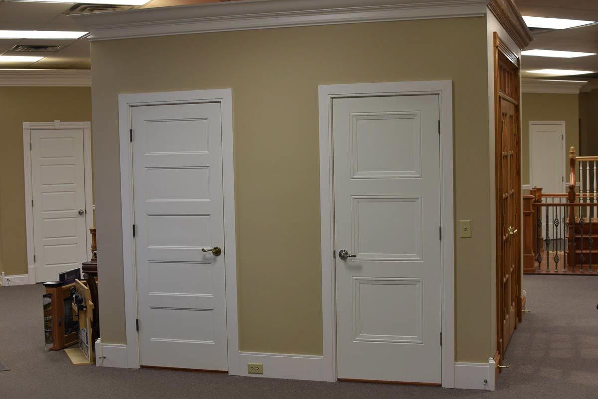 Three interior doors: white, panel doors on beige wall with a wooden door visible in the background.