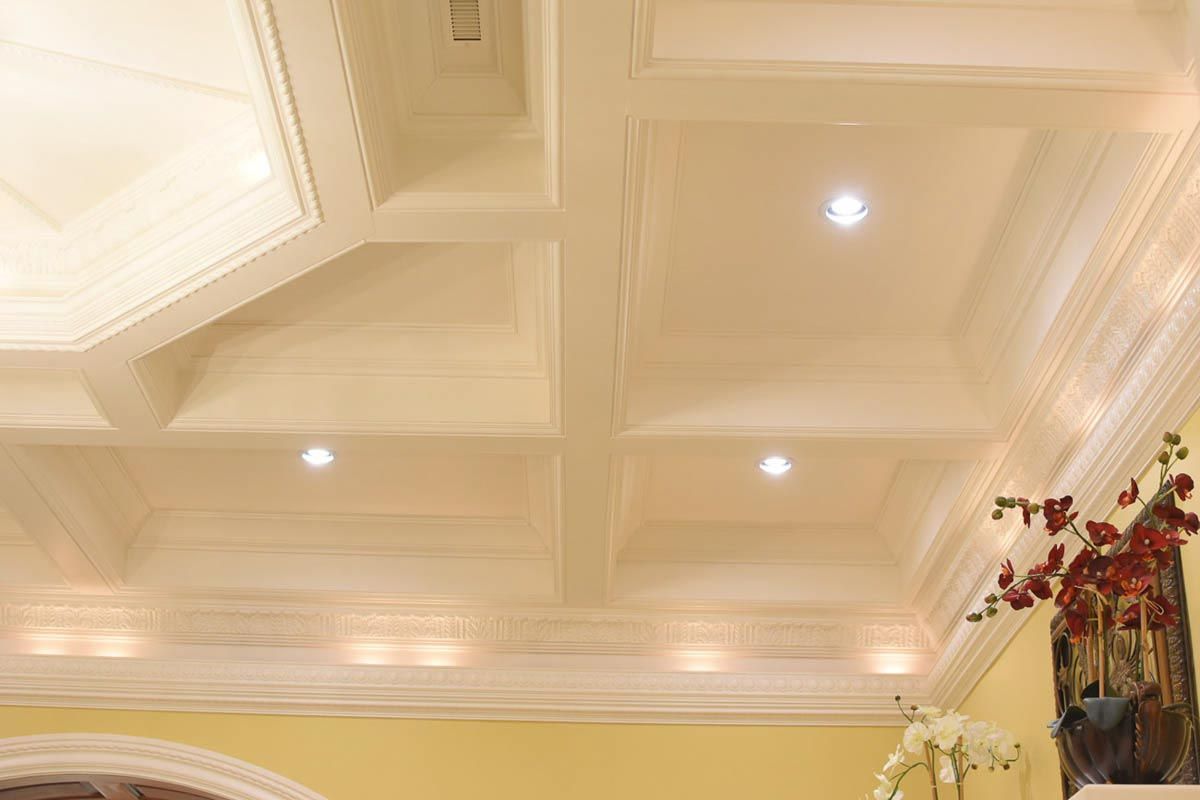 Ornate, coffered, white ceiling with recessed lighting.