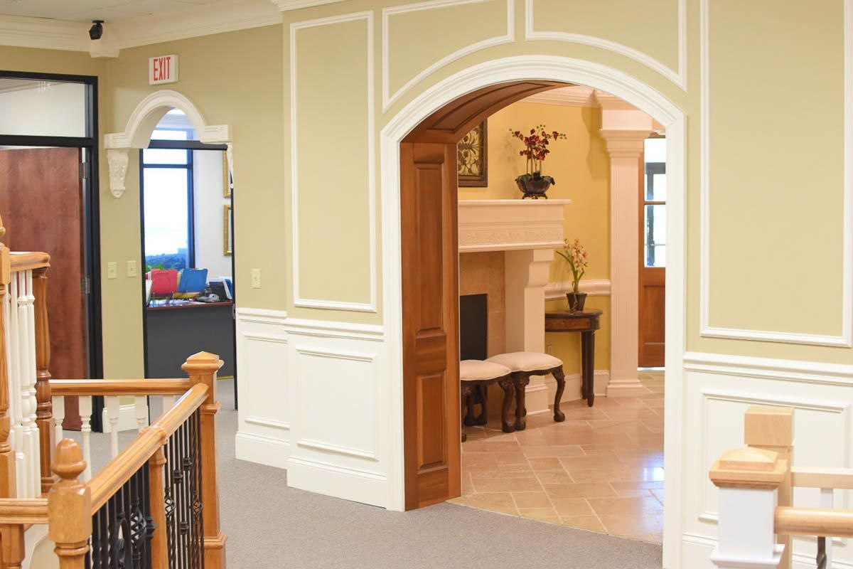 Hallway with arched doorways, ornate trim, and a fireplace.
