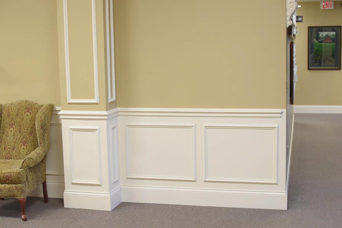 Wall with cream paint and white wainscoting; an armchair sits to the left.