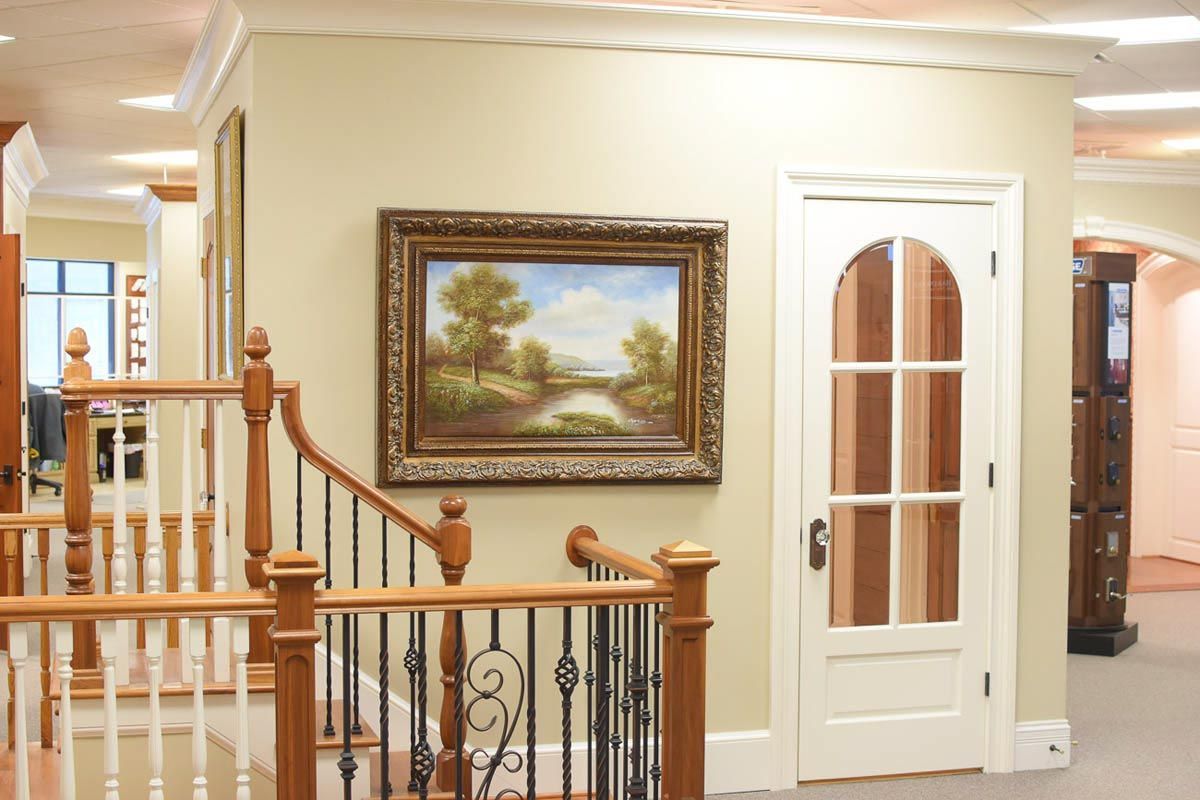 Hallway with staircase, painting, and white-paneled door with glass panes; beige walls and trim.