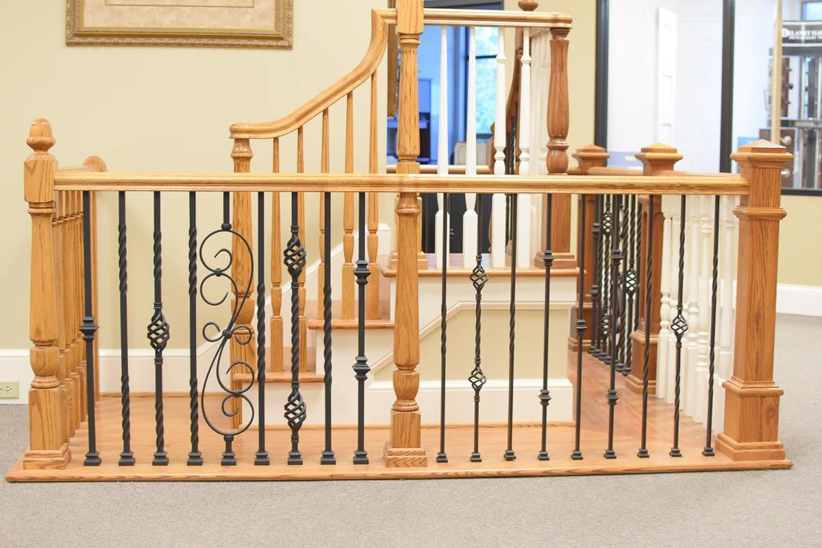 Wooden staircase with decorative iron balusters and railing.