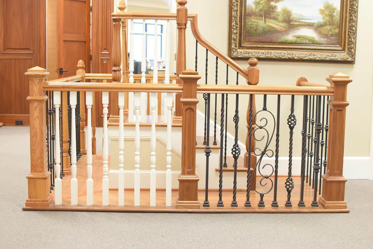 Wooden staircase with black and white spindles and decorative ironwork railing.
