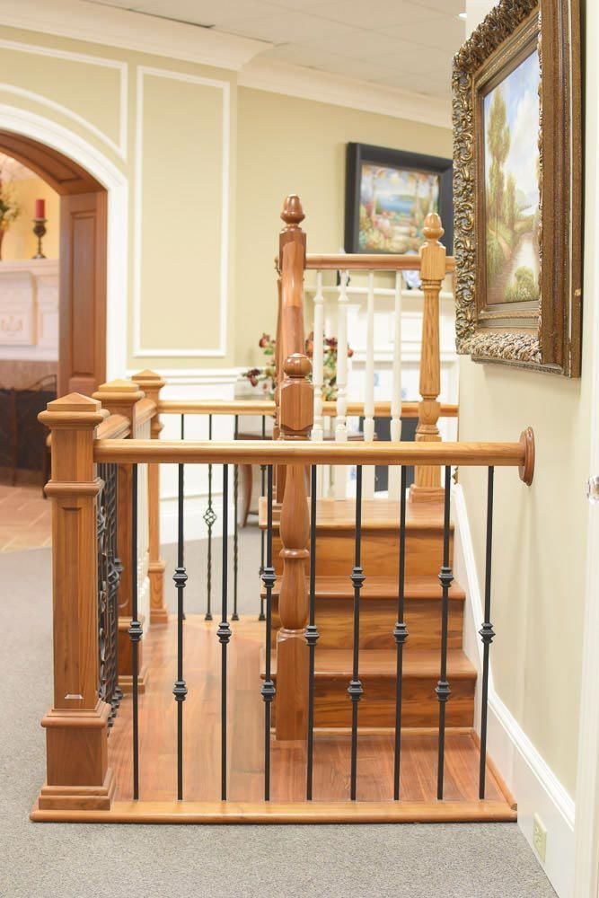 Wooden staircase with black iron spindles and framed artwork on a cream wall.