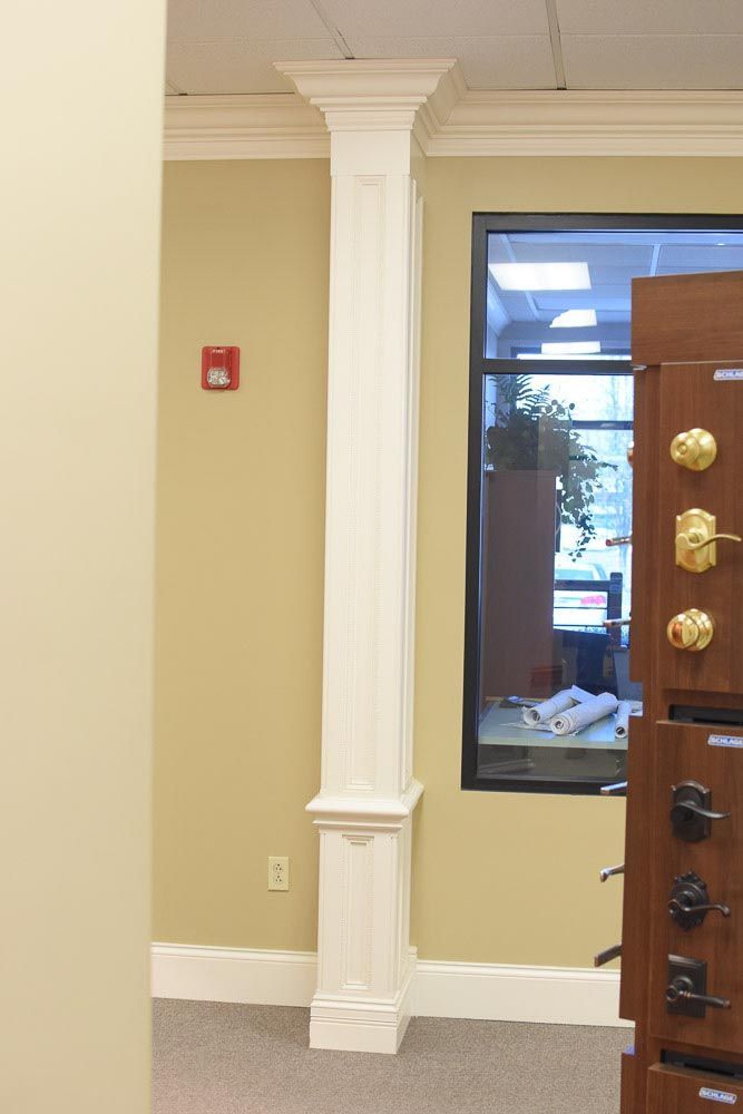 White architectural column in a room with tan walls and a window.