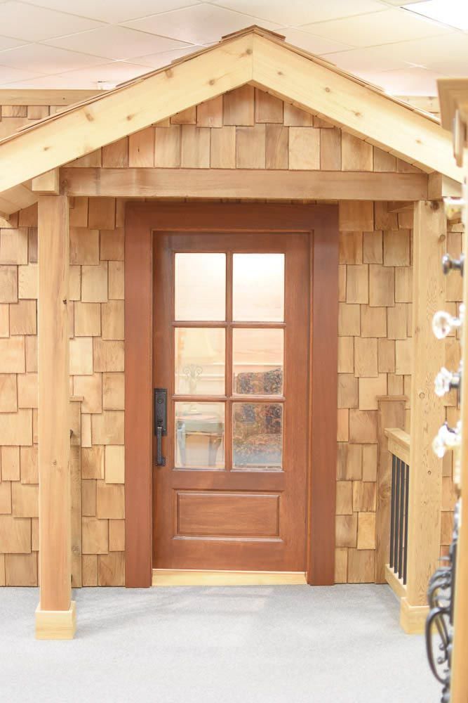 Wooden door with six panes, covered entry, and cedar shingle siding.