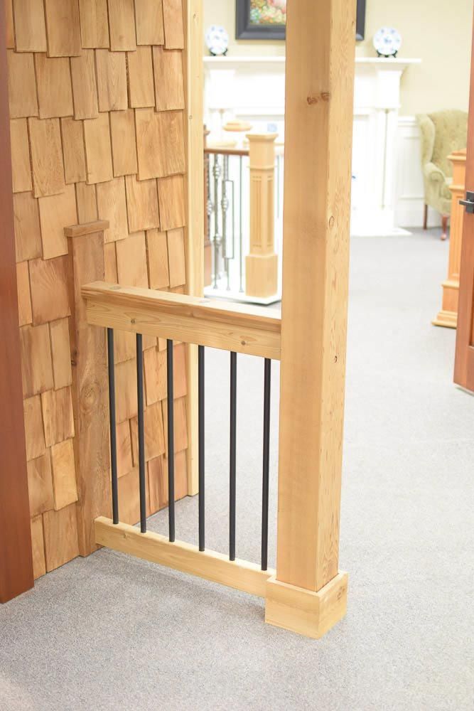 Wooden staircase with black metal bars, cedar shingle wall, and carpeted floor.