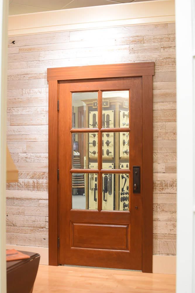 Wooden door with glass panes, brown frame, set in a light-colored wood paneled wall.