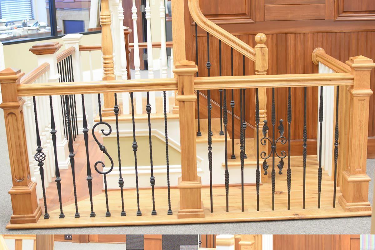 Wooden staircase with black metal balusters and ornate detail.
