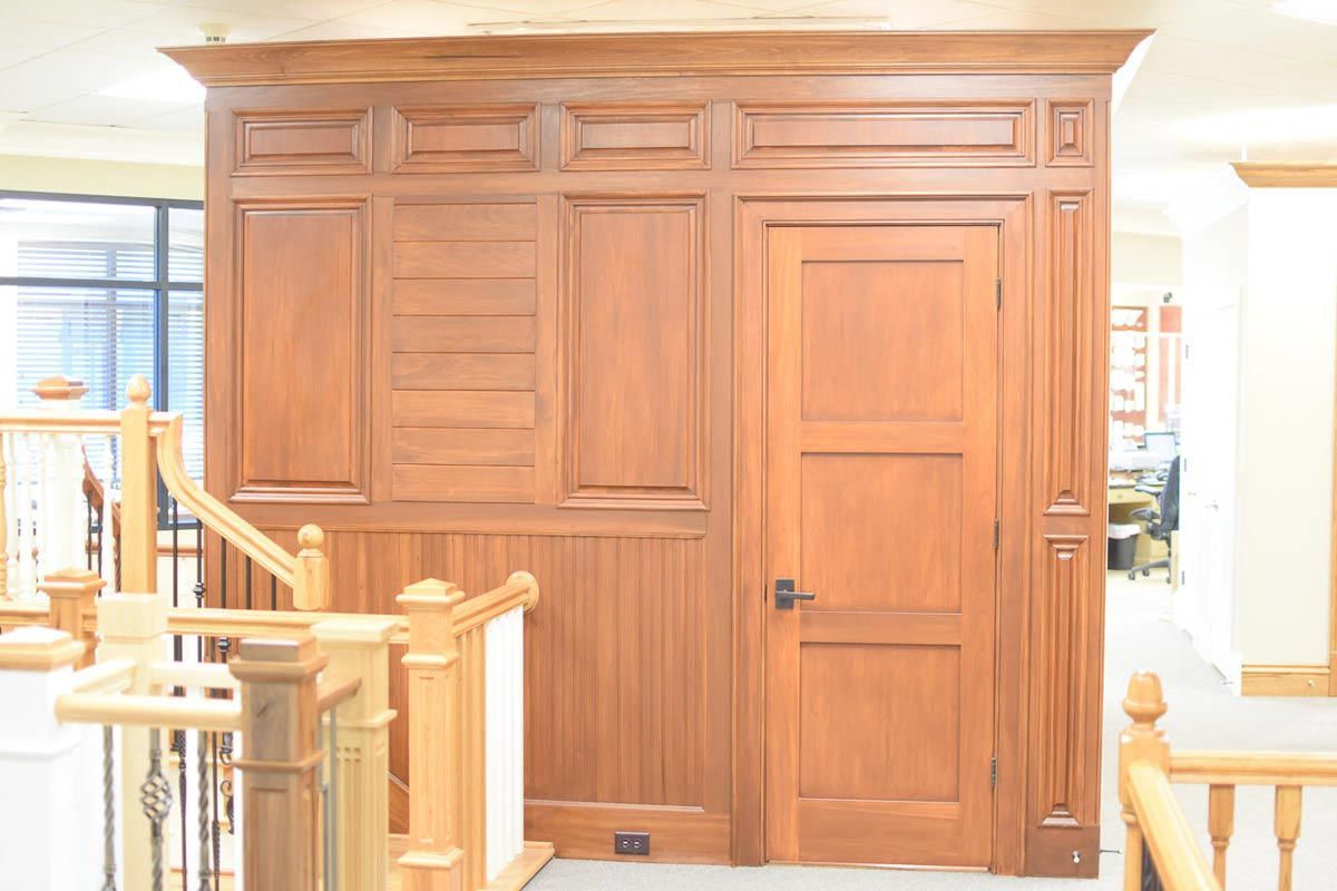 Wooden wall paneling with a door, decorative moldings, and a staircase visible on the left.