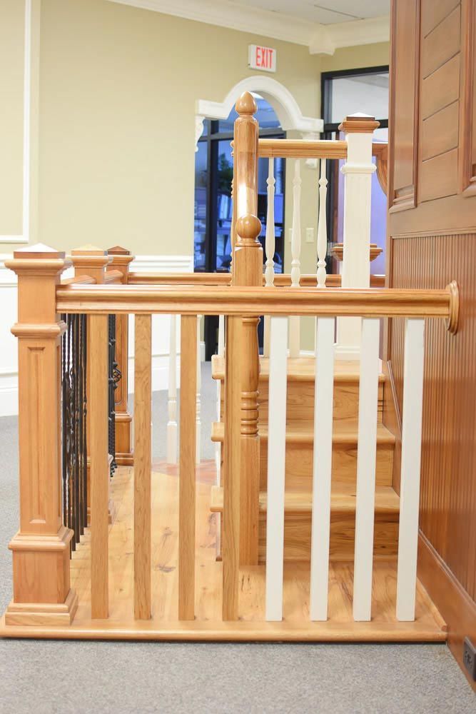 Staircase railing samples with various baluster and handrail styles displayed indoors.