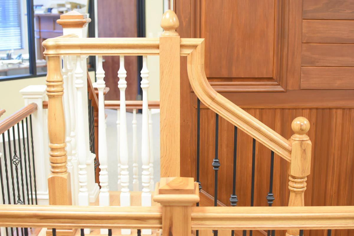 Wooden staircase with light-colored railing and banister. Dark brown door on right. Interior shot.