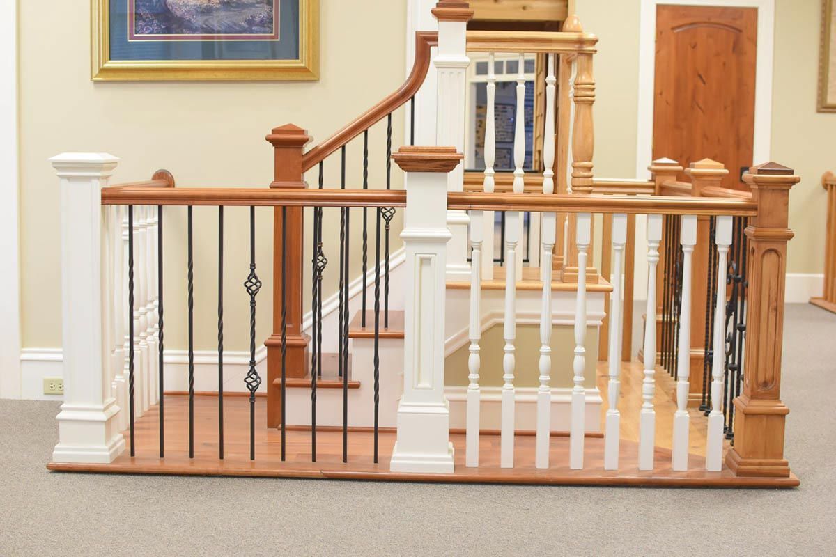 Staircase with wooden handrails, white and brown balusters, black wrought iron spindles.
