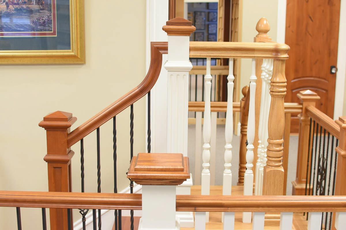 Wooden staircase with white and brown balusters, a curved handrail, and black iron spindles.