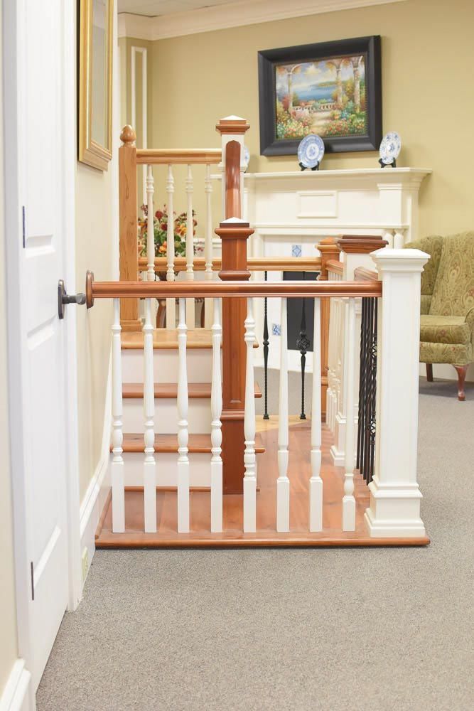 Staircase with wooden railing, leading up to a landing. White and brown wood elements with neutral carpet.