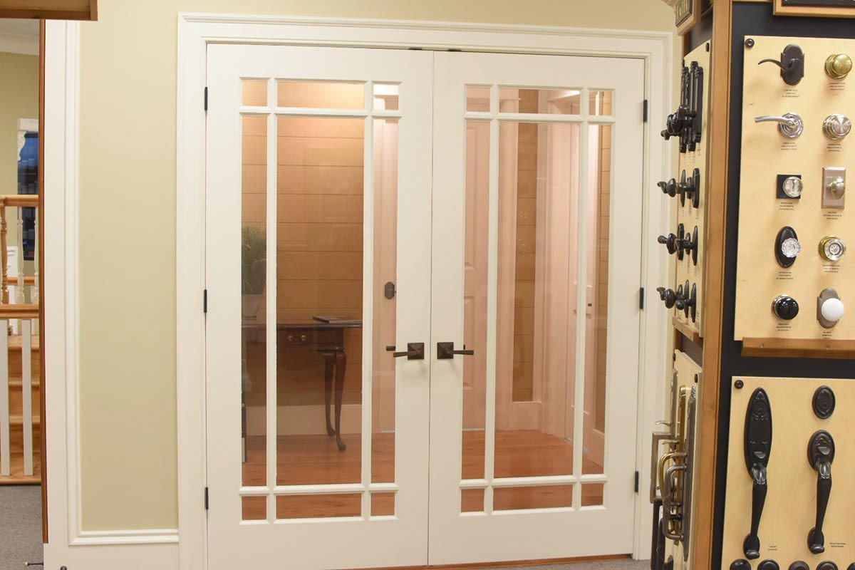 White French doors with glass panes, brown hardware, and a display of doorknobs on the right.