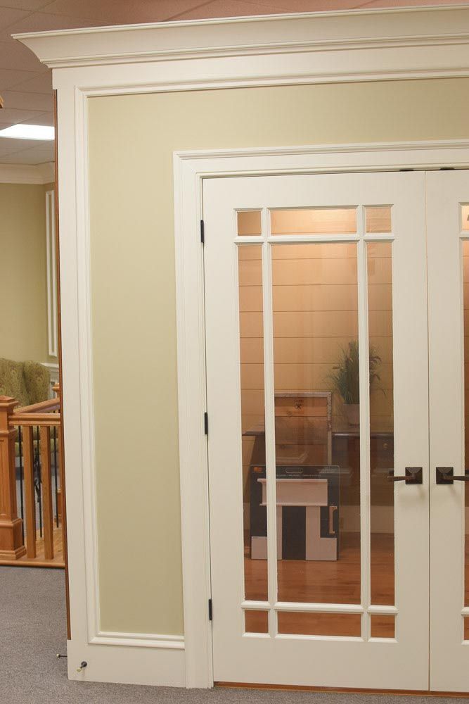 White-framed French doors with glass panes and a white trim surround, set against a light green wall.