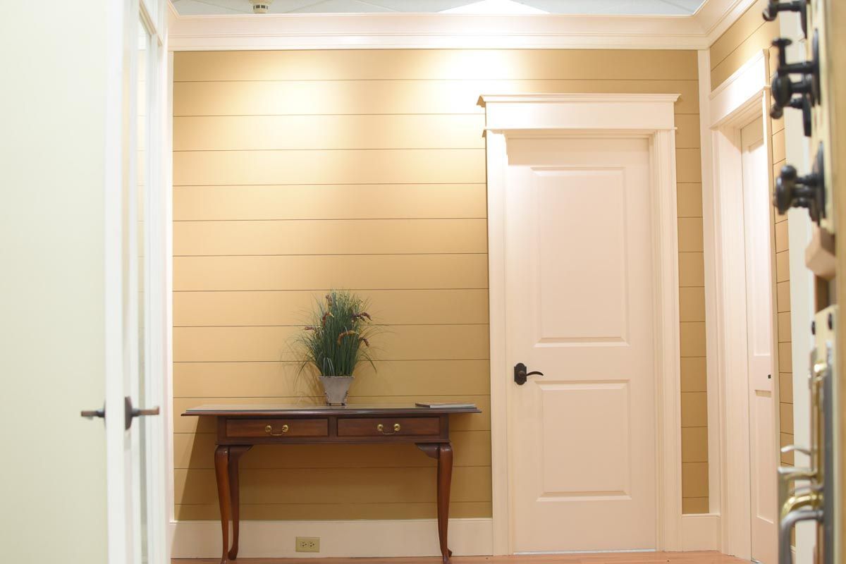 Entryway with yellow walls, white doors, and a table with a plant.