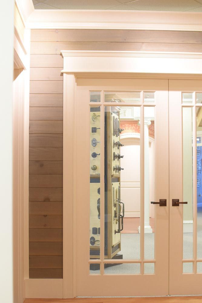 Double glass doors with grid design, tan frame. Wooden paneling on the wall. Brown handles. Bright room.