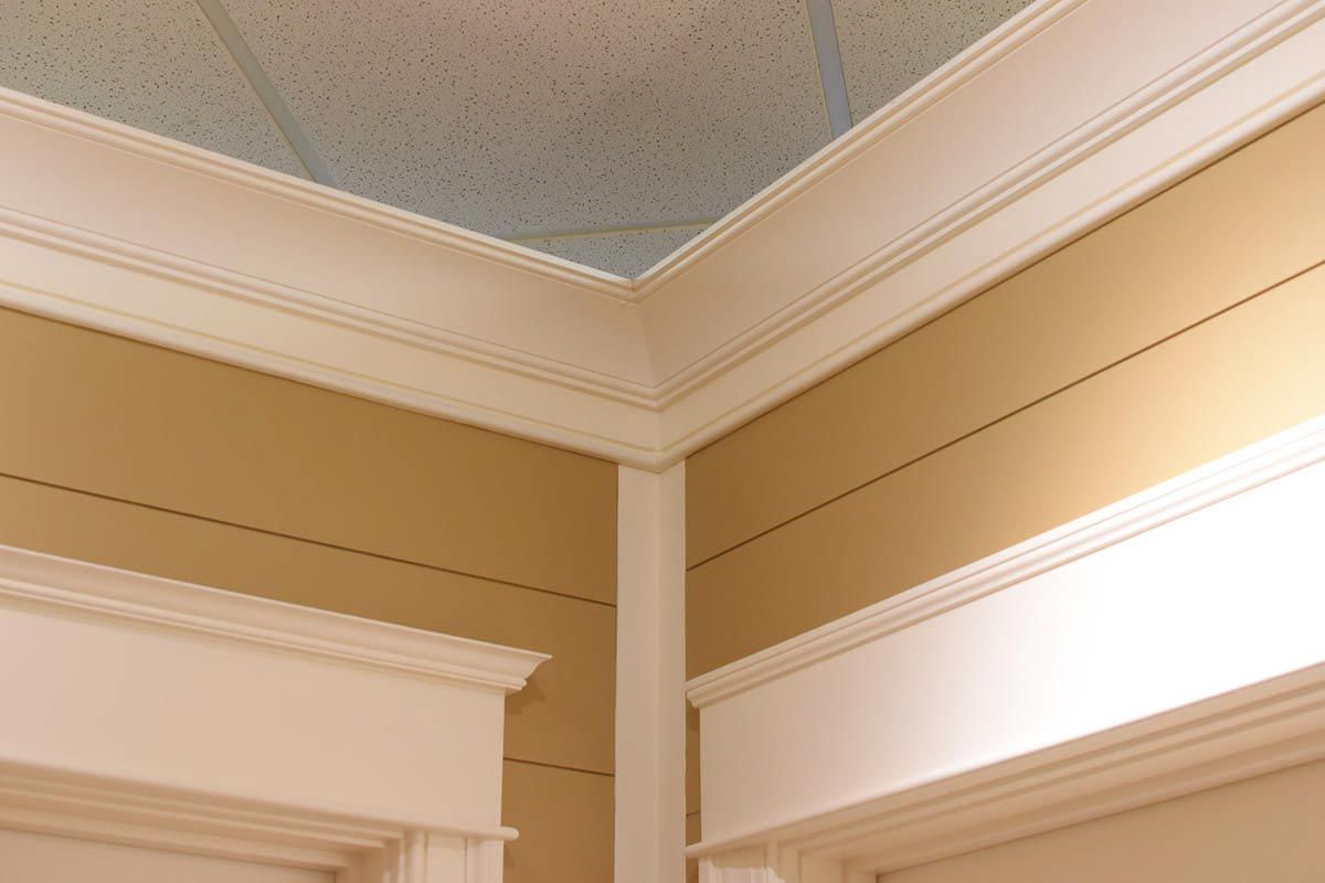 Corner of a room with tan walls, white crown molding, and a textured ceiling.