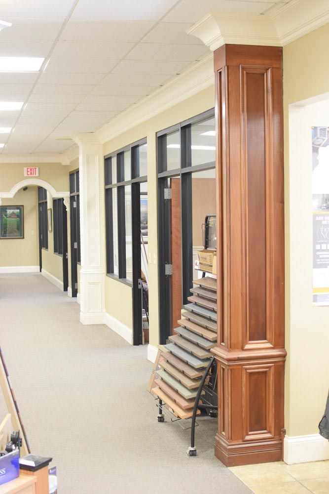 Hallway with brown wooden pillar, windows, and chairs stacked against the wall.