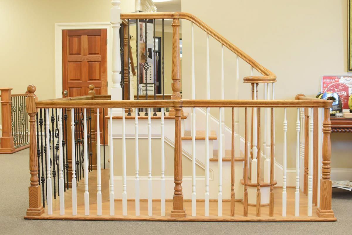 Staircase with light wood railing and white spindles, leading up to a landing.