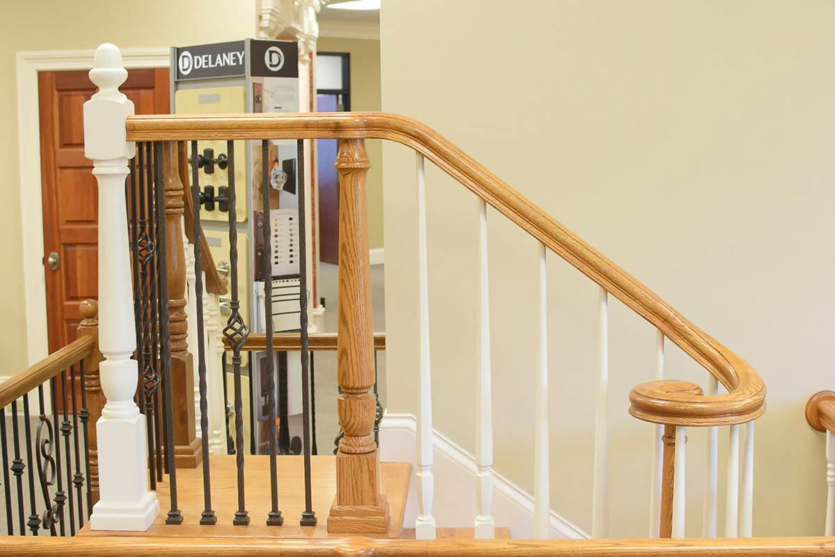 Wooden staircase with white spindles, oak railing, and ornamental iron balusters.
