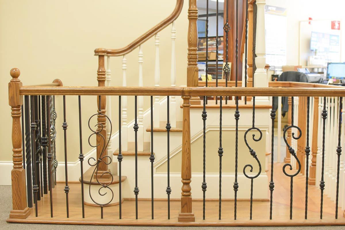 Oak and black iron railing on a staircase landing. White spindles and curved wooden handrail.