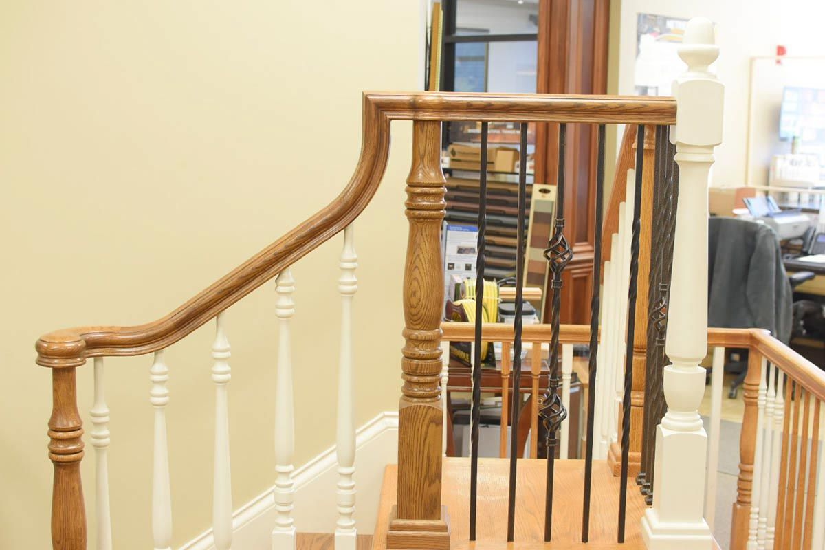 Wooden staircase with brown handrail, white balusters, and black metal spindles.