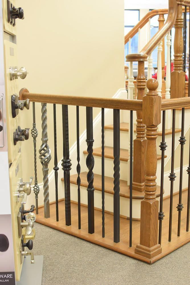 Staircase with wooden handrails and black metal balusters; showroom setting.