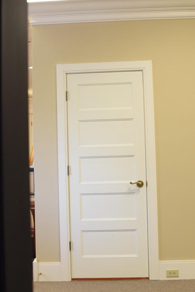 White, panel door in a room with light beige walls and a white door frame.