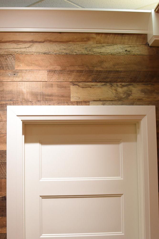 White door with white frame set against a rustic, weathered wood panel wall.