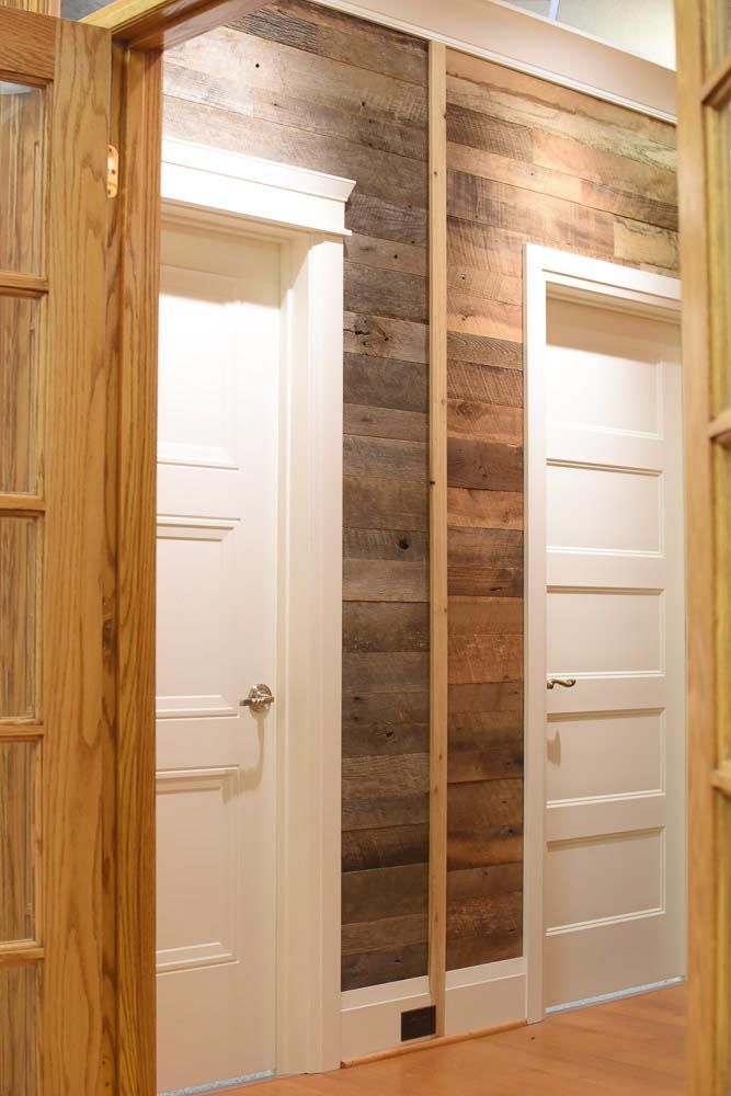 Two white doors flanking a wood-paneled wall. Wooden door frames and flooring.