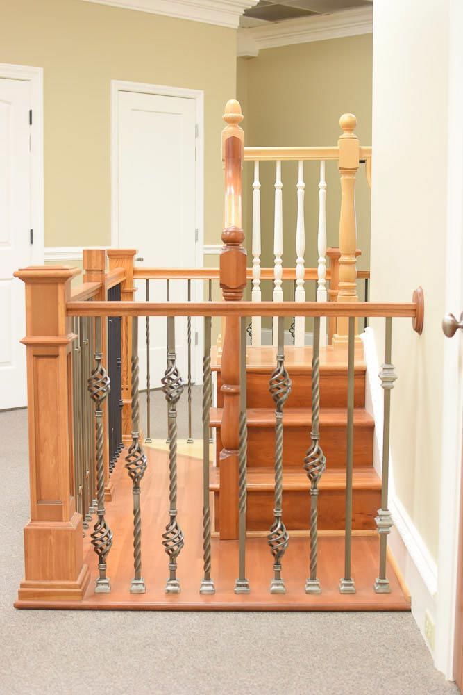 Wooden staircase with wrought iron balusters and wood handrails, beige walls, carpet.