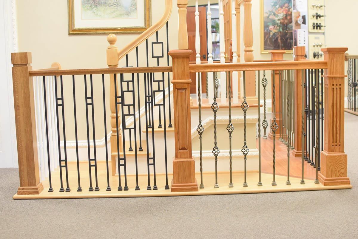 Wooden staircase with black metal railings, leading up. Beige walls with paintings.