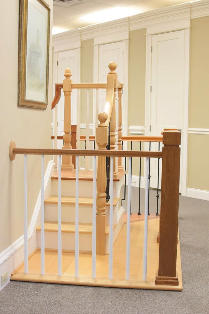 Staircase with wooden handrails and white vertical bars, leading to a second level in a building.
