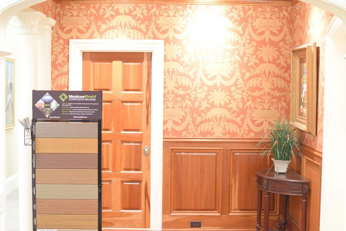 A wooden door and walls with paneling, wallpaper, and a small table with a plant.