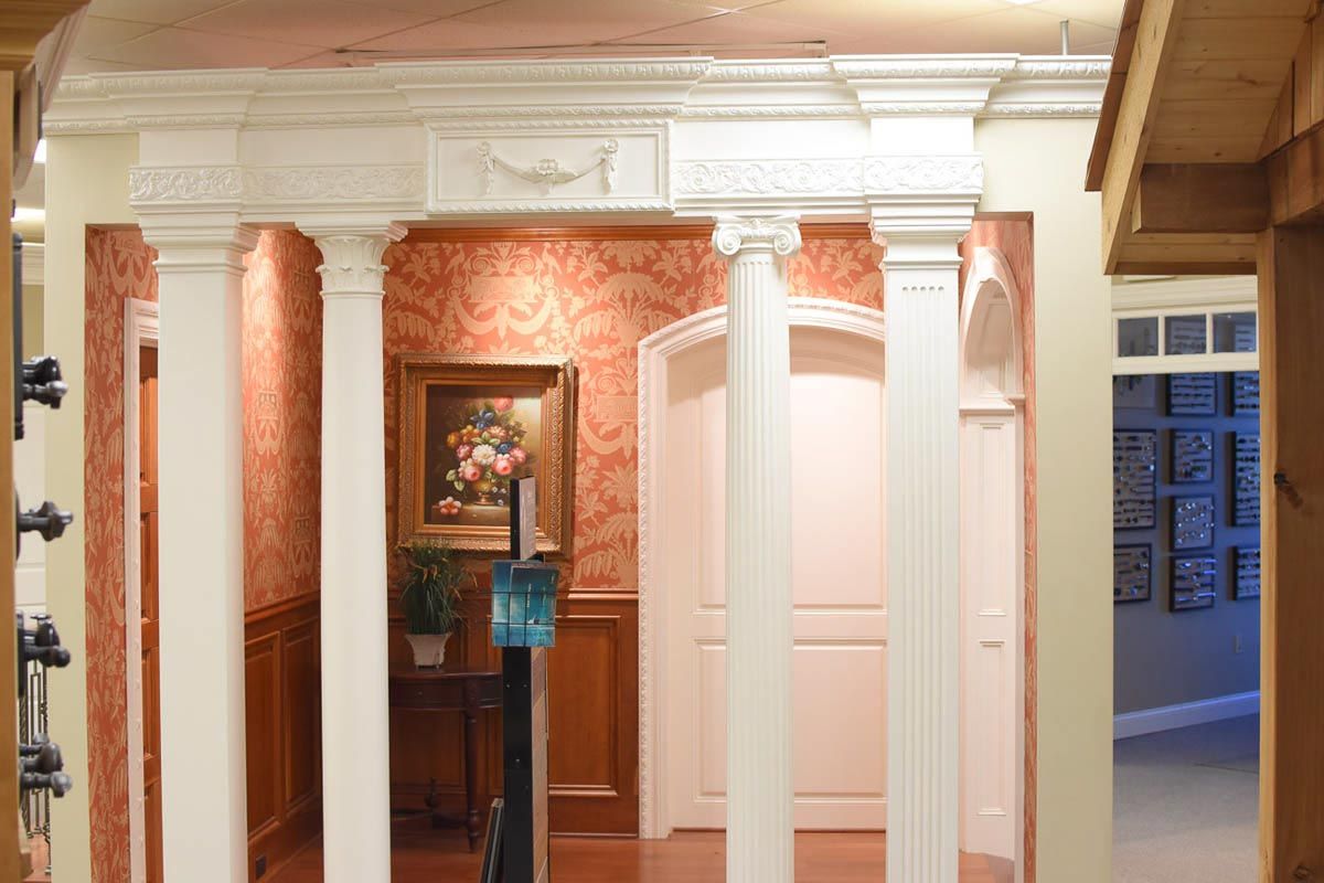 Interior with white columns, red wallpaper, artwork, and multiple doorways.