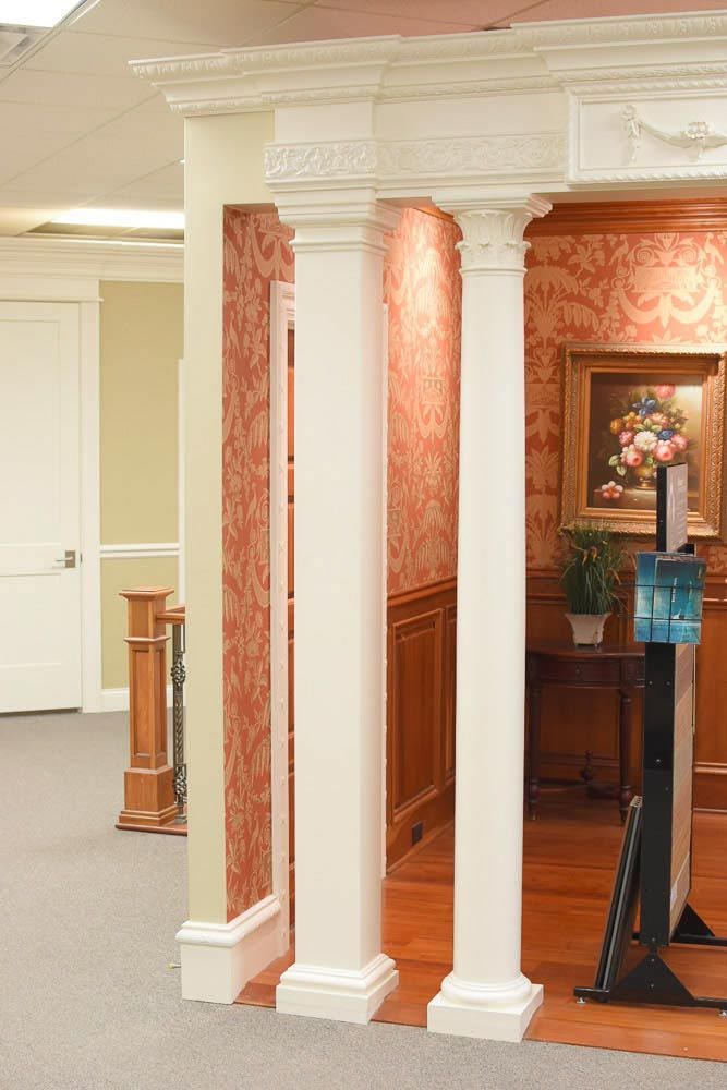 Hallway with white columns and red patterned wallpaper.