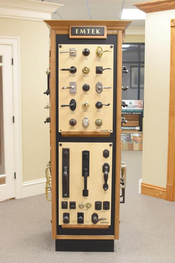 Door hardware display cabinet with EMTEK logo, showcasing various door handles and locksets.
