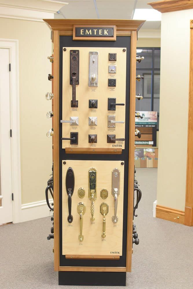 EMTEK door hardware display in a showroom, showing various handles and knobs.