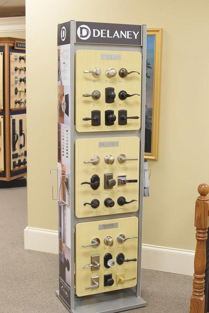 Display of Delaney door hardware samples in a store. Several styles in silver, black and gold.