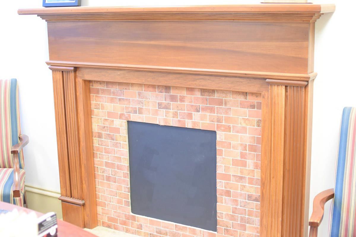 Wooden fireplace with brick-like tile surround and a black interior.