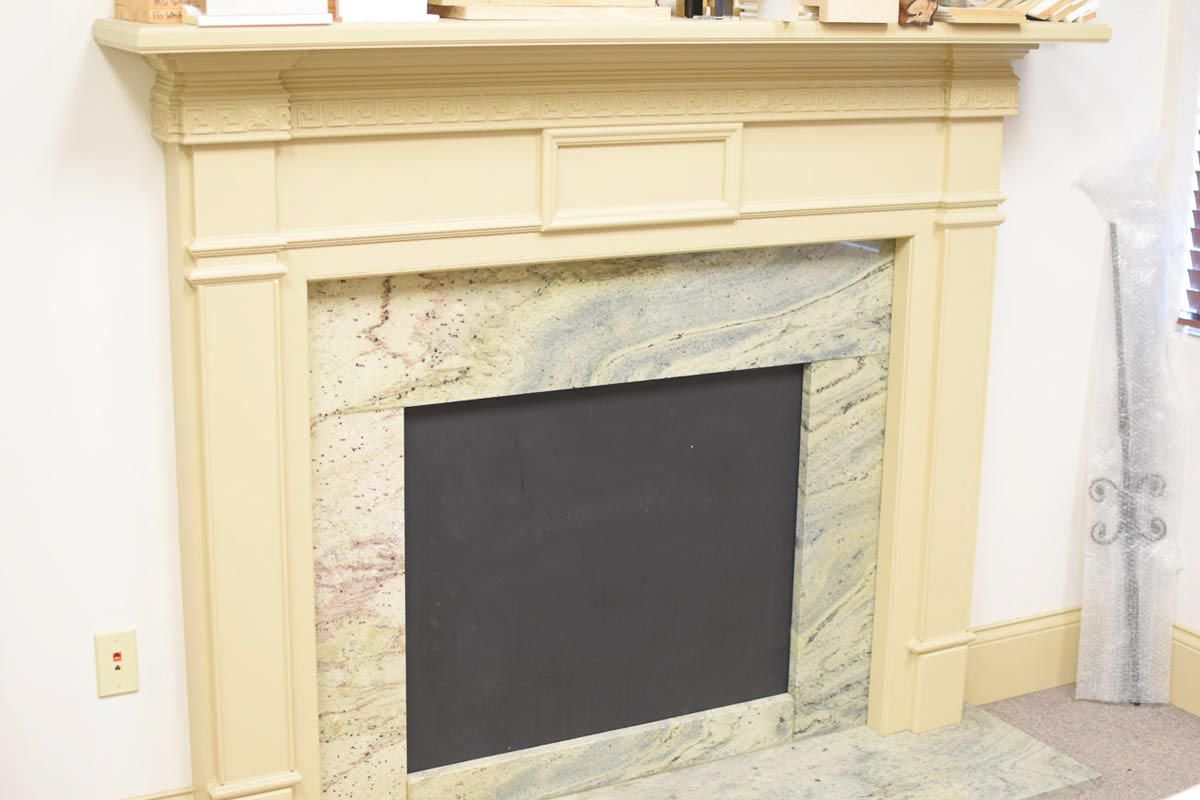 Fireplace with light yellow mantel and marble surround. Black interior.