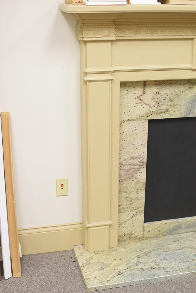 Beige fireplace with marble surround and black firebox.