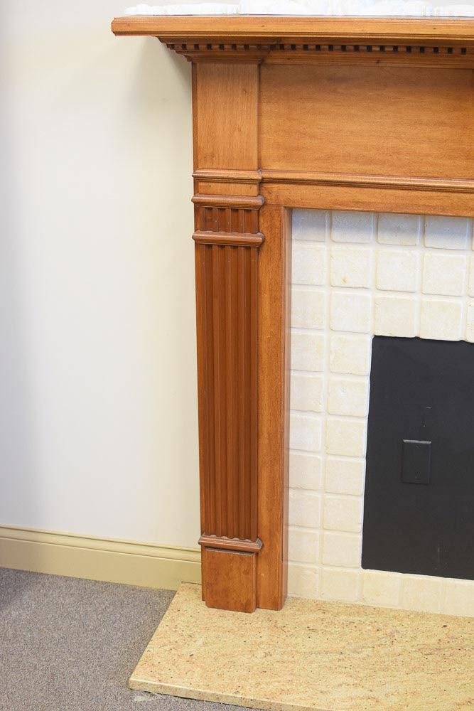 Wooden fireplace with fluted column detail and white tiled interior.